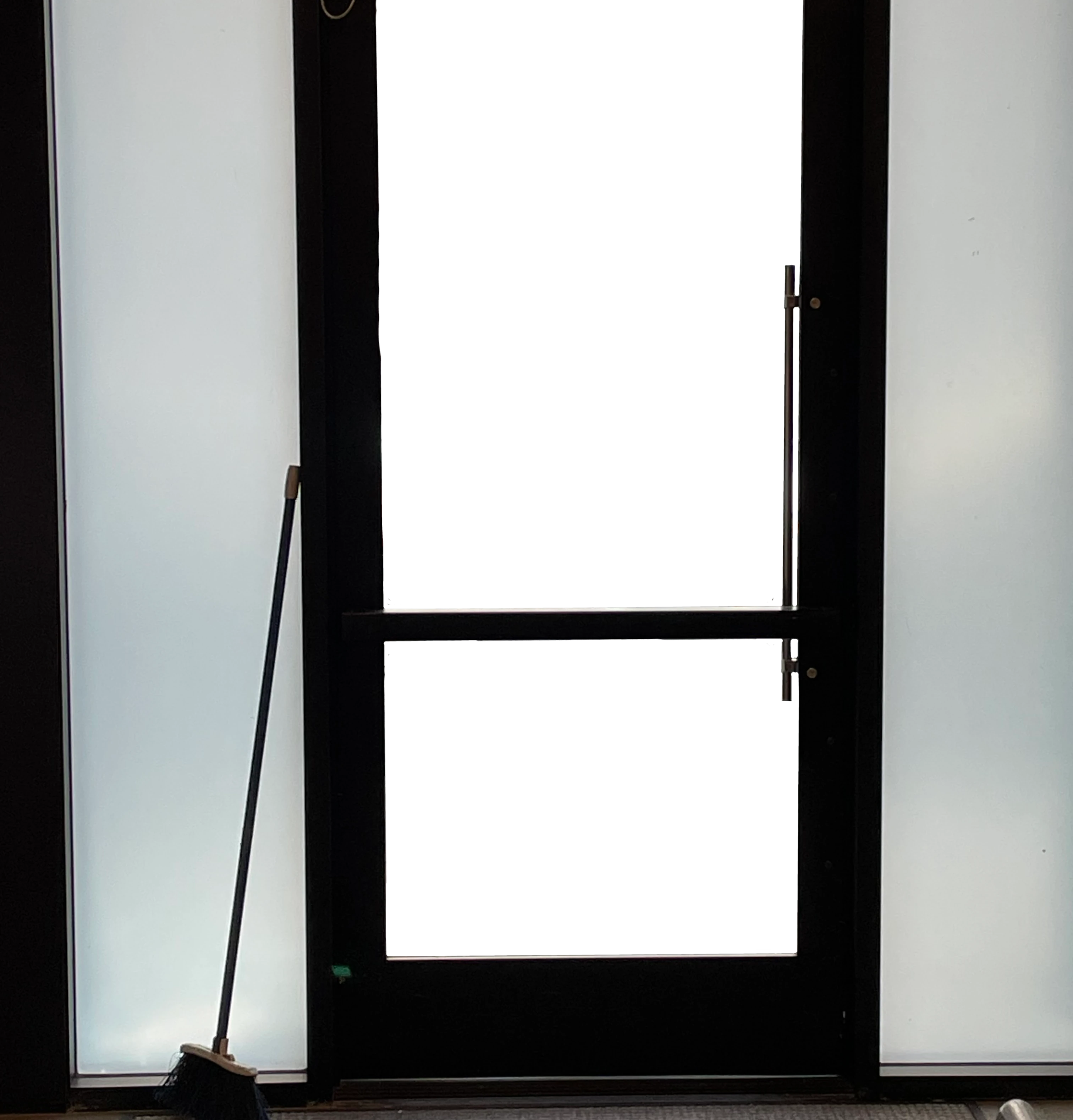 a busted opaque glass door with the handle blocking access and broom